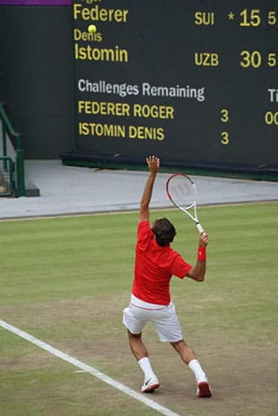 Roger Federer serving on a grass tennis court