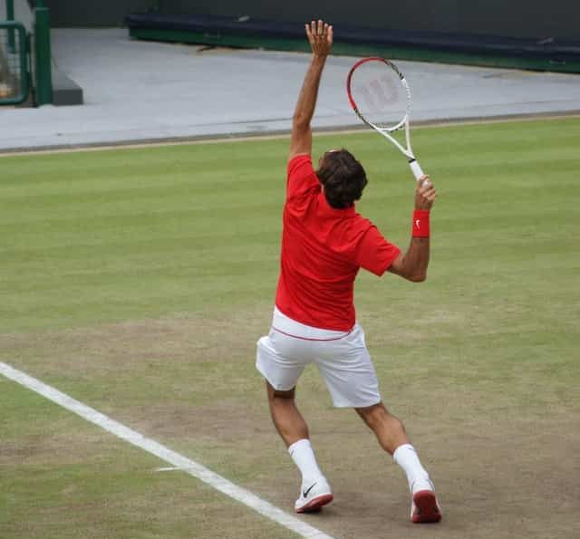 Roger Federer serving on a grass tennis court