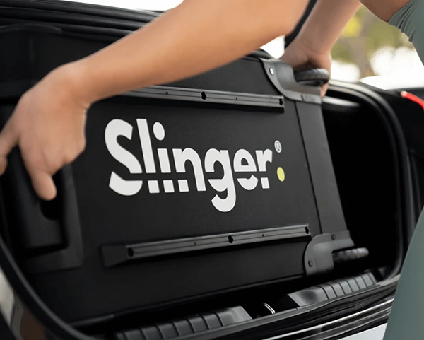 a person holding a slingerbag tennis ball machine